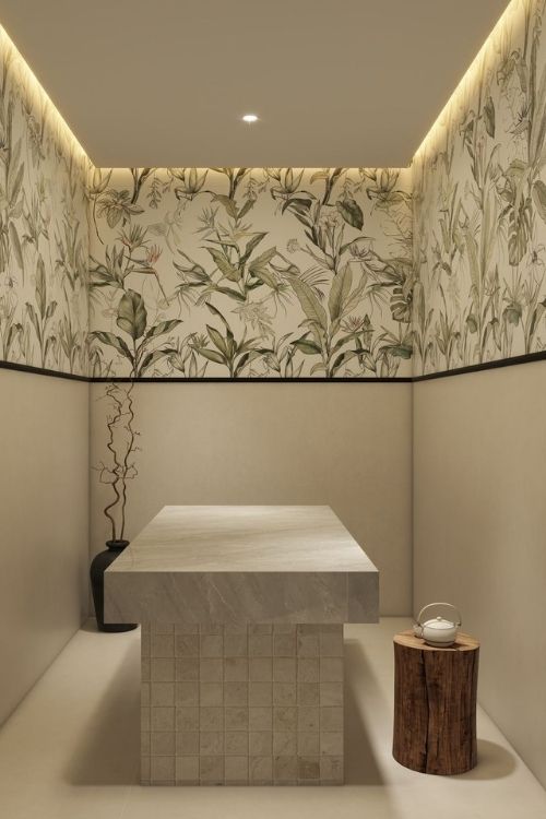 Luxurious Moroccan bath or body treatment room at Luckin Spa Abu Dhabi, featuring a central stone slab and elegant botanical wallpaper for a serene experience.